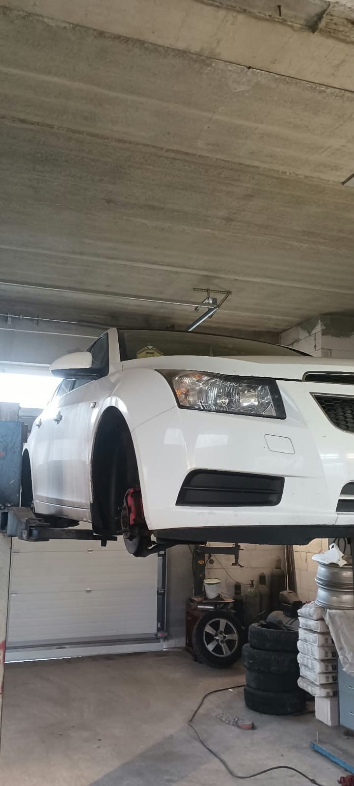 Bílé auto na zvedáku s sundaným kolem